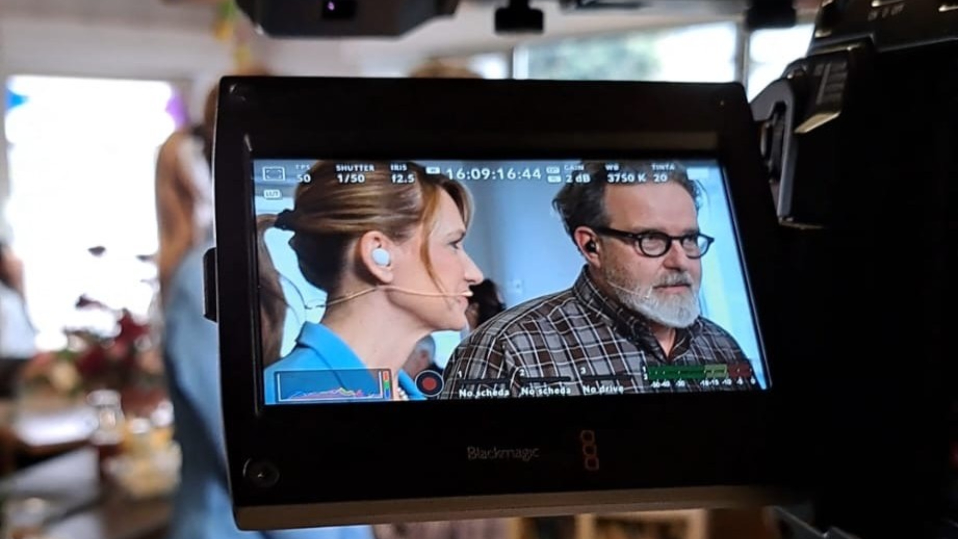 Persone riprese in un monitor durante una registrazione video, concentrati in una conversazione.